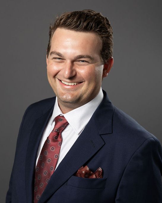 Studio headshot, navy suit, charcoal backdrop